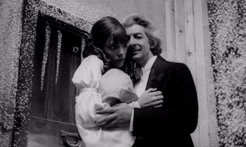 Movie still from “Wonderwall” (1968), directed by Joe Massot – A man and a woman hugging each other in front of a building; Close Up shot, Low angle