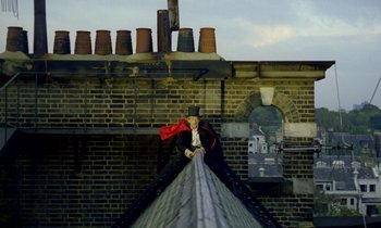 Movie still from “Wonderwall” (1968), directed by Joe Massot – A man wearing a red cape standing on top of a building; Extreme Wide shot, Low angle