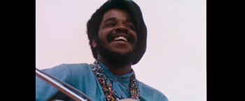 Movie still from “Woodstock” (1970), directed by Michael Wadleigh – A person with a beard smiling; Close Up shot, Low angle