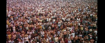 Movie still from “Woodstock” (1970), directed by Michael Wadleigh – A large crowd of people gathered together in a large room; Extreme Wide shot, High angle