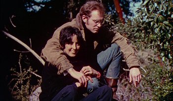 Movie still from “Woodstock” (1970), directed by Michael Wadleigh – A man sitting next to a woman on the ground; Medium shot, Low angle