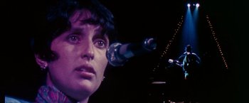 Movie still from “Woodstock” (1970), directed by Michael Wadleigh – A person with a microphone; Close Up shot, Over the shoulder angle