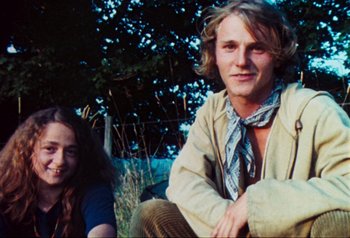 Movie still from “Woodstock” (1970), directed by Michael Wadleigh – A man and a woman sitting on the grass; Medium shot, Low angle
