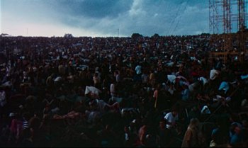 Movie still from “Woodstock” (1970), directed by Michael Wadleigh – A crowd of people sitting on the grass; Extreme Wide shot, High angle