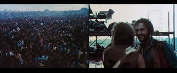 Movie still from “Woodstock” (1970), directed by Michael Wadleigh – A large crowd of people are gathered in a stadium; Wide shot, High angle