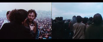 Movie still from “Woodstock” (1970), directed by Michael Wadleigh – A man holding a camera in front of a large crowd of onlookers; Medium shot, High angle