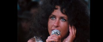 Movie still from “Woodstock” (1970), directed by Michael Wadleigh – A person holding a microphone; Close Up shot, High angle