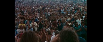 Movie still from “Woodstock” (1970), directed by Michael Wadleigh – A large crowd of people gathered in a field; Extreme Wide shot, High angle