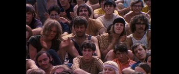 Movie still from “Woodstock” (1970), directed by Michael Wadleigh – A large group of people sitting in a crowd; Medium shot, High angle