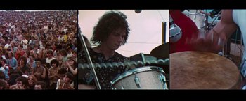 Movie still from “Woodstock” (1970), directed by Michael Wadleigh – A man playing drums in front of a crowd; Medium shot, High angle