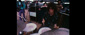 Movie still from “Woodstock” (1970), directed by Michael Wadleigh – A man playing drums in front of an audience; Medium shot, High angle