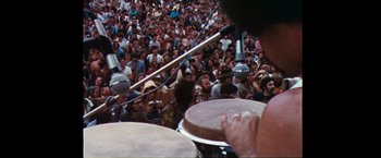 Movie still from “Woodstock” (1970), directed by Michael Wadleigh – A crowd of people watching a man play drums; Extreme Wide shot, High angle