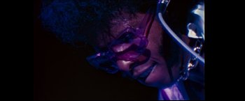 Movie still from “Woodstock” (1970), directed by Michael Wadleigh – A person wearing glasses and a purple shirt; Extreme Close Up shot, Low angle