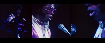 Movie still from “Woodstock” (1970), directed by Michael Wadleigh – A person speaking on a microphone; Close Up shot, Low angle