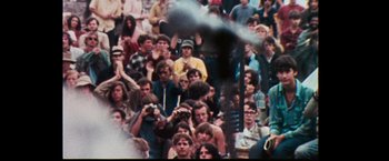 Movie still from “Woodstock” (1970), directed by Michael Wadleigh – A crowd of people watching a man do a trick on a skateboard; Medium shot, High angle