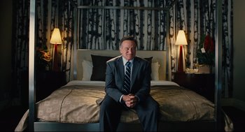 A man in a suit sitting on top of a bed