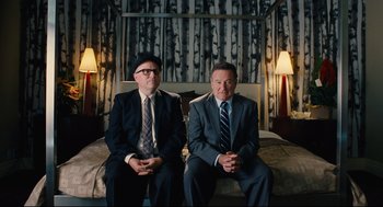 A couple of men sitting on top of a bed in a room