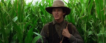 Movie still from “Wyatt Earp” (1994), directed by Lawrence Kasdan – A young man in a hat standing in a corn field; Close Up shot, Low angle