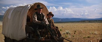Movie still from “Wyatt Earp” (1994), directed by Lawrence Kasdan – Two men sitting on a covered wagon in the desert; Wide shot, Low angle