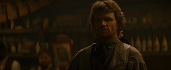 Movie still from “Wyatt Earp” (1994), directed by Lawrence Kasdan – A man with long blonde hair wearing a suit and tie; Close Up shot, Over the shoulder angle