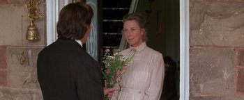 Movie still from “Wyatt Earp” (1994), directed by Lawrence Kasdan – A woman in a white dress holding a bunch of flowers; Medium shot, Over the shoulder angle