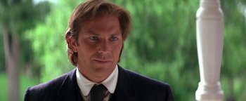 Movie still from “Wyatt Earp” (1994), directed by Lawrence Kasdan – A man in a suit and tie looking at the camera; Close Up shot, Over the shoulder angle