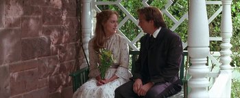 Movie still from “Wyatt Earp” (1994), directed by Lawrence Kasdan – A man and a woman sitting on a bench holding flowers; Medium shot, Over the shoulder angle