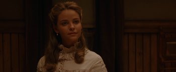 Movie still from “Wyatt Earp” (1994), directed by Lawrence Kasdan – A young woman in a white dress looking at the camera; Close Up shot, Over the shoulder angle