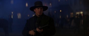 Movie still from “Wyatt Earp” (1994), directed by Lawrence Kasdan – A man in a black hat holding a gun in his hand; Close Up shot, Low angle