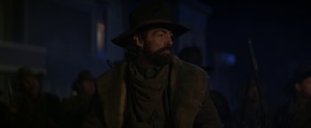 Movie still from “Wyatt Earp” (1994), directed by Lawrence Kasdan – A man with a long beard wearing a hat; Medium shot, Over the shoulder angle