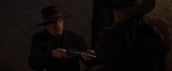 Movie still from “Wyatt Earp” (1994), directed by Lawrence Kasdan – A man in a hat is holding a gun; Close Up shot, Over the shoulder angle