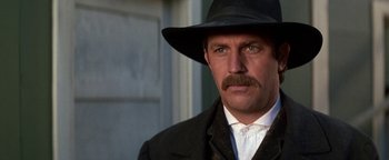Movie still from “Wyatt Earp” (1994), directed by Lawrence Kasdan – A person wearing a hat and a suit; Close Up shot, Low angle