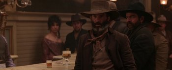 Movie still from “Wyatt Earp” (1994), directed by Lawrence Kasdan – A group of people sitting at a table with drinks; Medium shot, Over the shoulder angle