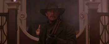 Movie still from “Wyatt Earp” (1994), directed by Lawrence Kasdan – A man with a hat holding a gun in his hand; Close Up shot, Low angle