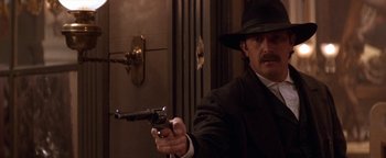 Movie still from “Wyatt Earp” (1994), directed by Lawrence Kasdan – A man holding a gun in a room; Close Up shot, Low angle