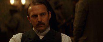 Movie still from “Wyatt Earp” (1994), directed by Lawrence Kasdan – A person wearing a suit and tie; Close Up shot, Over the shoulder angle