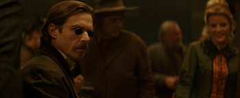 Movie still from “Wyatt Earp” (1994), directed by Lawrence Kasdan – A man with a goatee and a mustache wearing sunglasses; Close Up shot, Over the shoulder angle