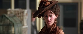 Movie still from “Wyatt Earp” (1994), directed by Lawrence Kasdan – A woman in a brown dress and a brown hat; Close Up shot, Low angle