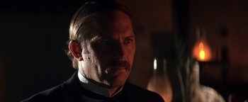 Movie still from “Wyatt Earp” (1994), directed by Lawrence Kasdan – A person wearing a suit and tie; Close Up shot, Over the shoulder angle