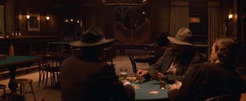 Movie still from “Wyatt Earp” (1994), directed by Lawrence Kasdan – A group of people sitting at a table playing cards; Medium shot, Over the shoulder angle