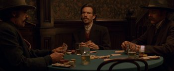 Movie still from “Wyatt Earp” (1994), directed by Lawrence Kasdan – A man sitting at a table with cards in front of him; Medium shot, Over the shoulder angle