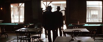 Movie still from “Wyatt Earp” (1994), directed by Lawrence Kasdan – Two men are standing in front of an open door; Wide shot, Low angle
