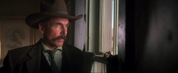 Movie still from “Wyatt Earp” (1994), directed by Lawrence Kasdan – A man in a cowboy hat looking out of a window; Close Up shot, Low angle