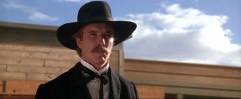 Movie still from “Wyatt Earp” (1994), directed by Lawrence Kasdan – A man in a black suit and a black hat; Close Up shot, Low angle