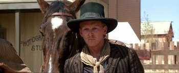 Movie still from “Wyatt Earp” (1994), directed by Lawrence Kasdan – A man wearing a green hat and a striped jacket; Close Up shot, Over the shoulder angle