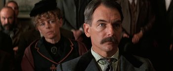Movie still from “Wyatt Earp” (1994), directed by Lawrence Kasdan – An older man with a mustache and a woman in the background; Close Up shot, Low angle