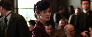 Movie still from “Wyatt Earp” (1994), directed by Lawrence Kasdan – A woman wearing a purple dress and a purple hat; Close Up shot, Over the shoulder angle