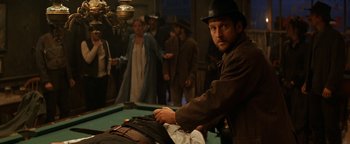 Movie still from “Wyatt Earp” (1994), directed by Lawrence Kasdan – A group of people standing next to a pool table; Medium shot, Over the shoulder angle