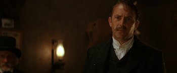 Movie still from “Wyatt Earp” (1994), directed by Lawrence Kasdan – A person wearing a suit and tie; Close Up shot, Low angle