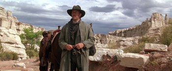 Movie still from “Wyatt Earp” (1994), directed by Lawrence Kasdan – A man standing next to a horse on a dirt road; Medium shot, Low angle